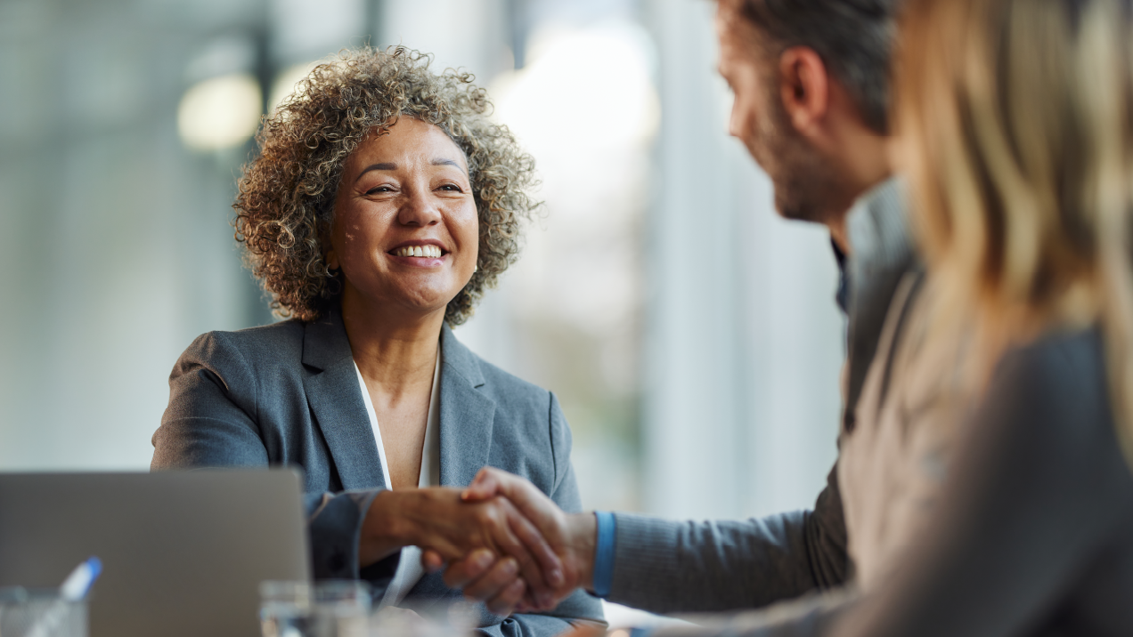 Smiling businesswoman shakes hands with client