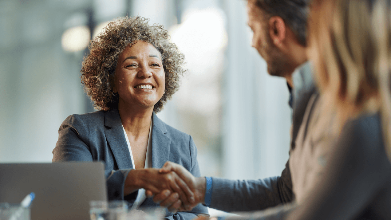 Smiling businesswoman shakes hands with client