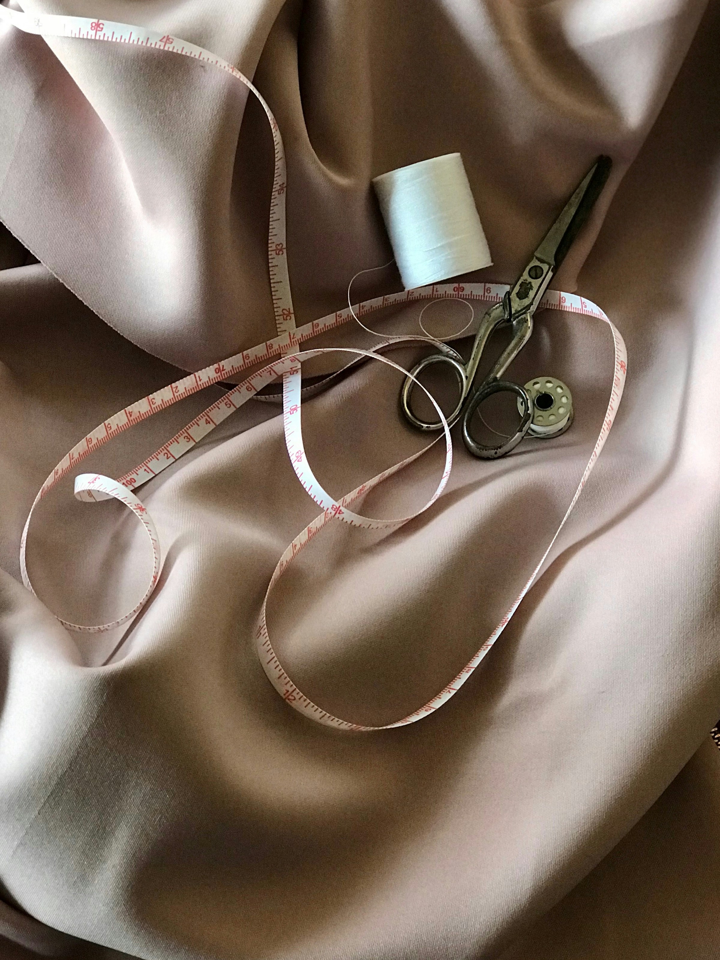 Fabric, spool of thread, scissors, measuring tape